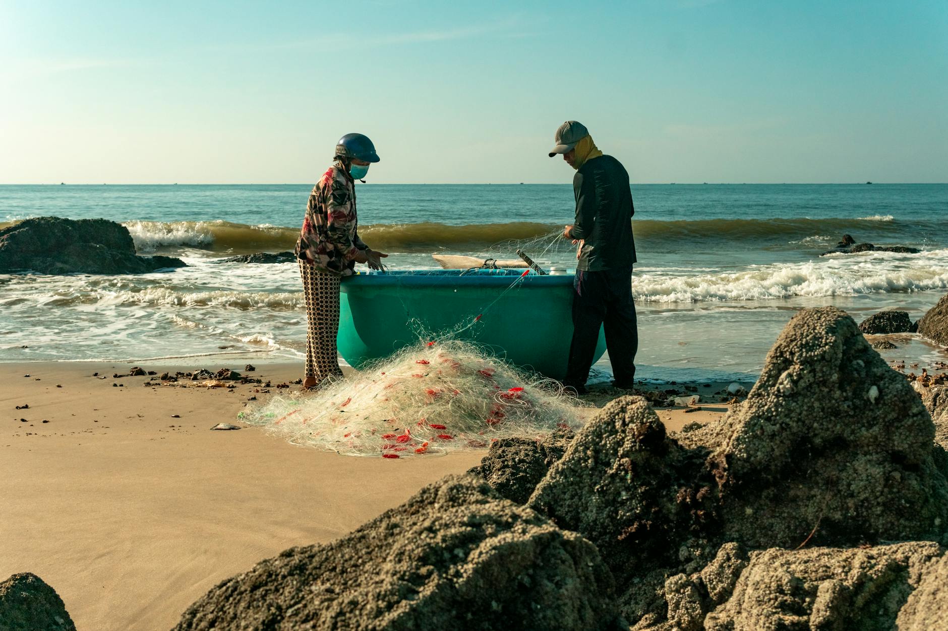 Dwóch wędkarzy rozplątuje sieci na plaży o wschodzie słońca
