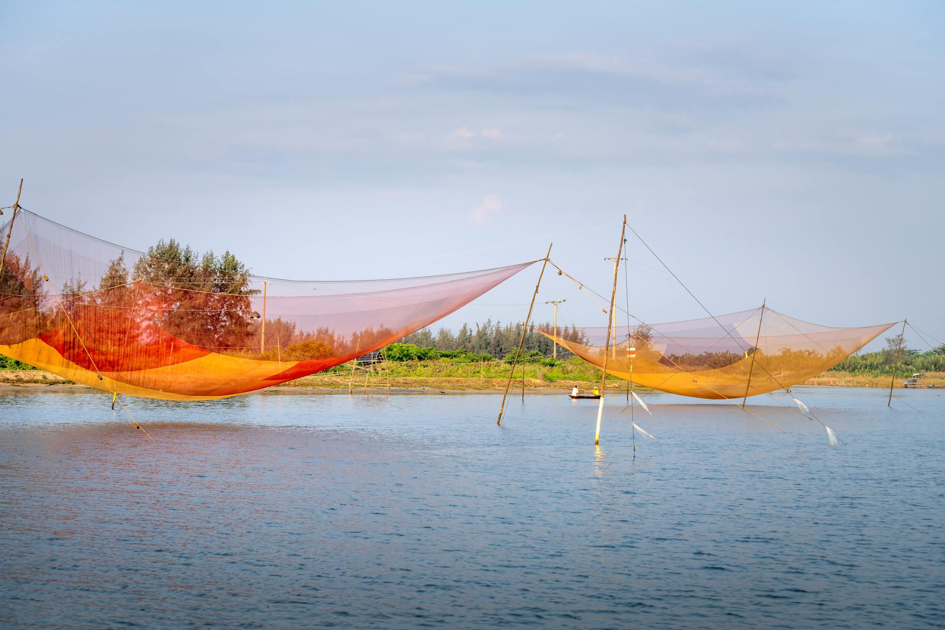 Kolorowe sieci rybackie rozpięte na bambusowych tyczkach nad rzeką
