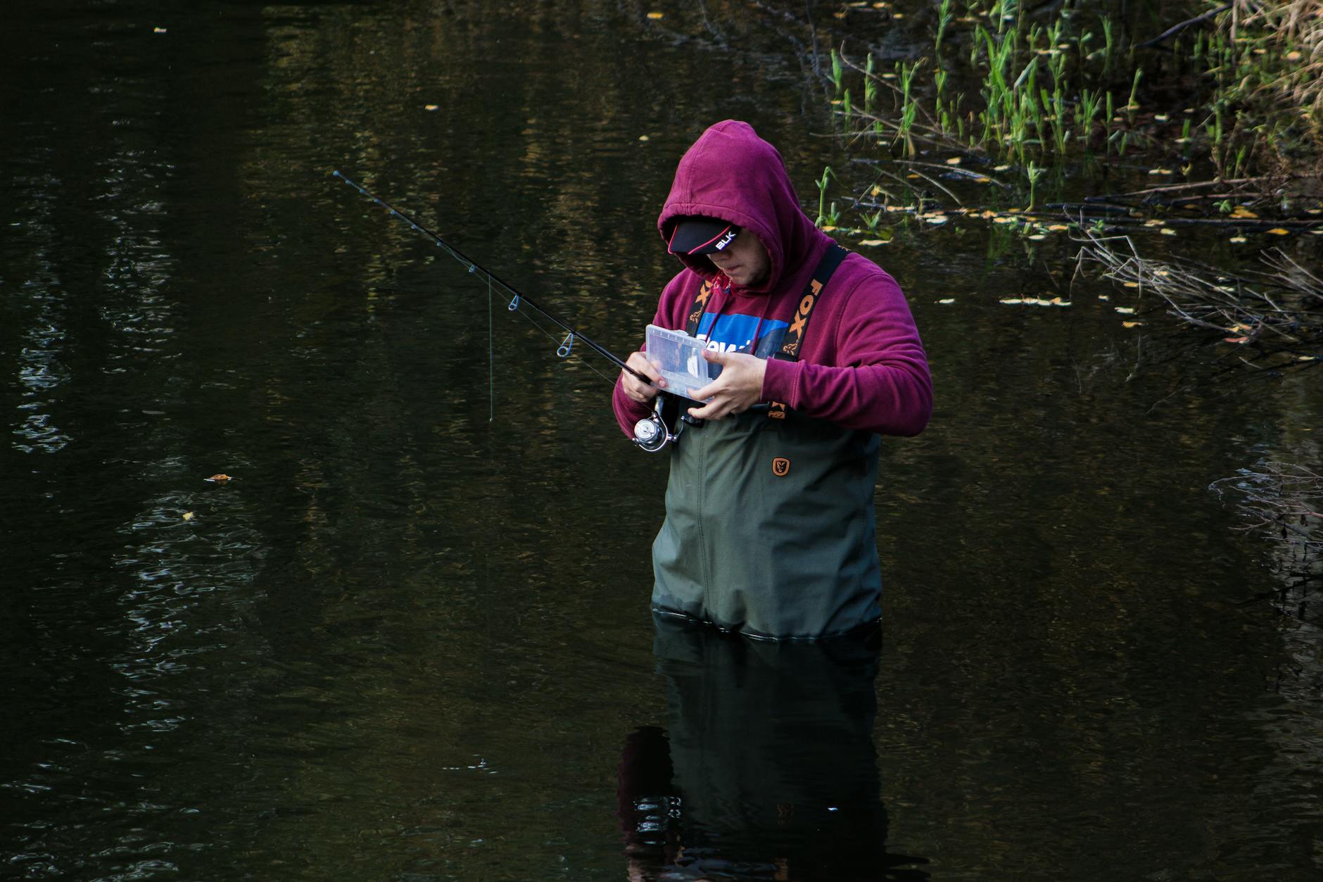 Wędkarz nad spokojną rzeką otoczoną zielenią Wędkarz nad spokojną rzeką otoczoną zielenią