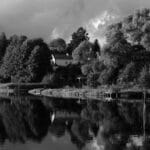 Wędkarz nad spokojnym jeziorem otoczonym jesiennymi drzewami