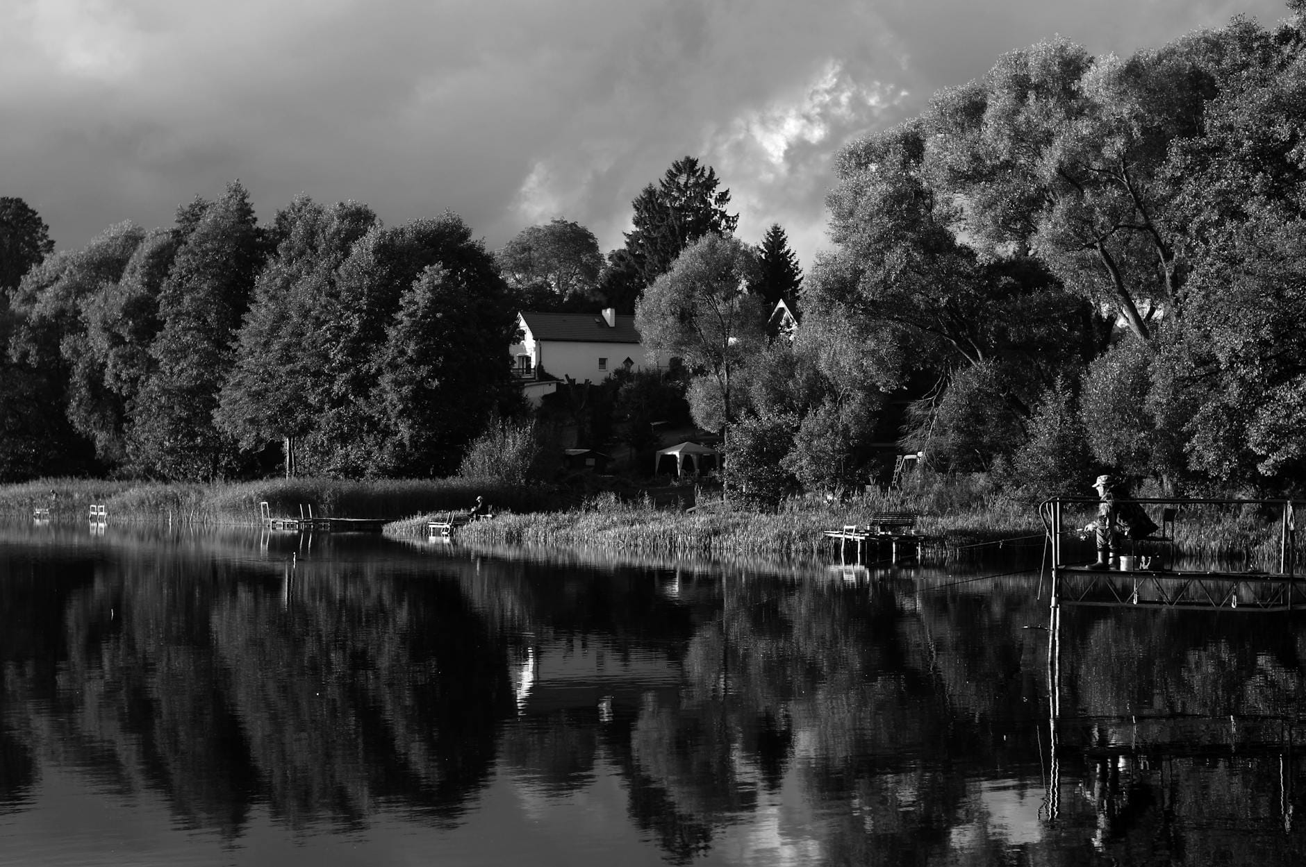 Wędkarz nad spokojnym jeziorem otoczonym jesiennymi drzewami