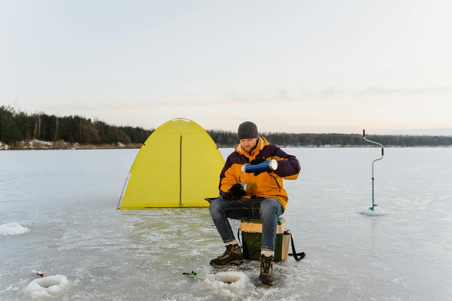 Wędkarz podlodowy obok namiotu na zamarzniętym jeziorze zimą