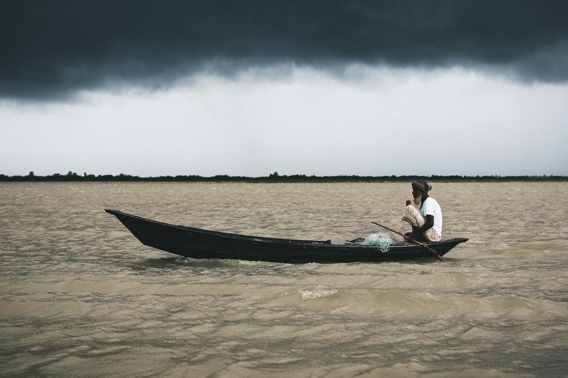Wędkarz samotnie łowiący z łodzi na rzece podczas burzowych chmur
