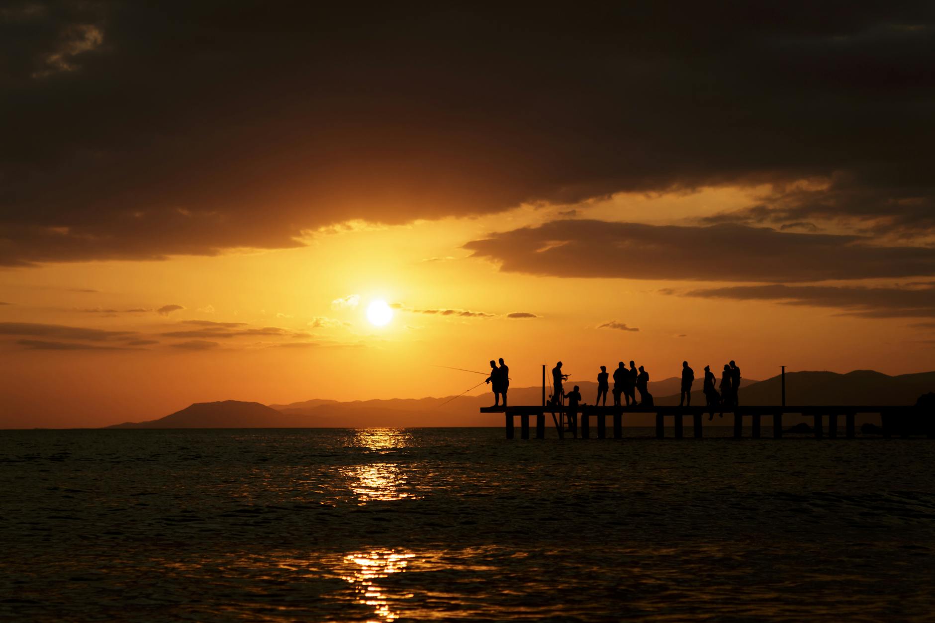 Wędkarze na molo podczas spokojnego zachodu słońca nad wodą