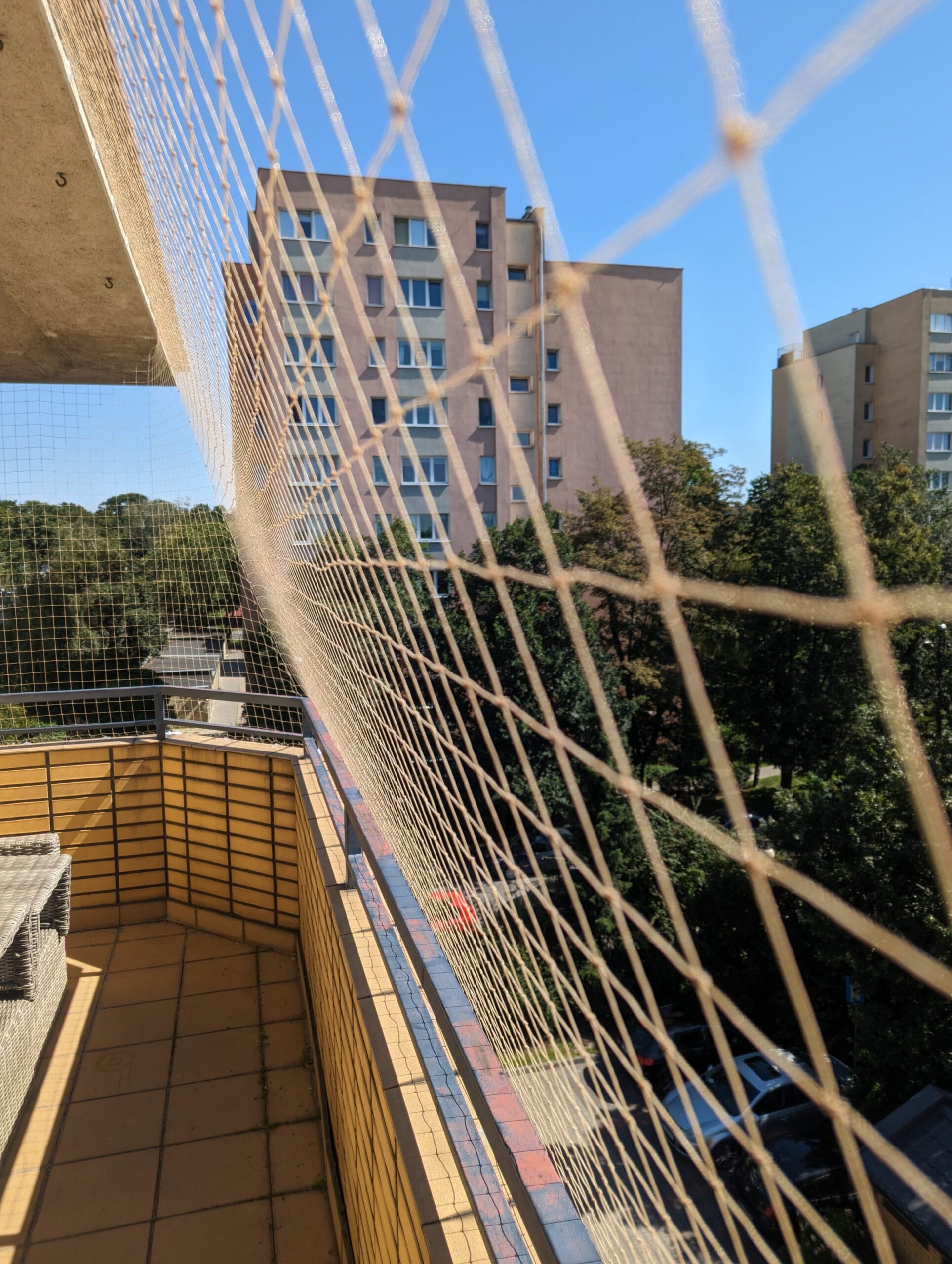 zbliżenie na siatkę balkonową montowaną na skomplikowanym balkonie