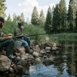 Dwóch wędkarzy nad leśnym brzegiem rzeki podczas spokojnego łowienia