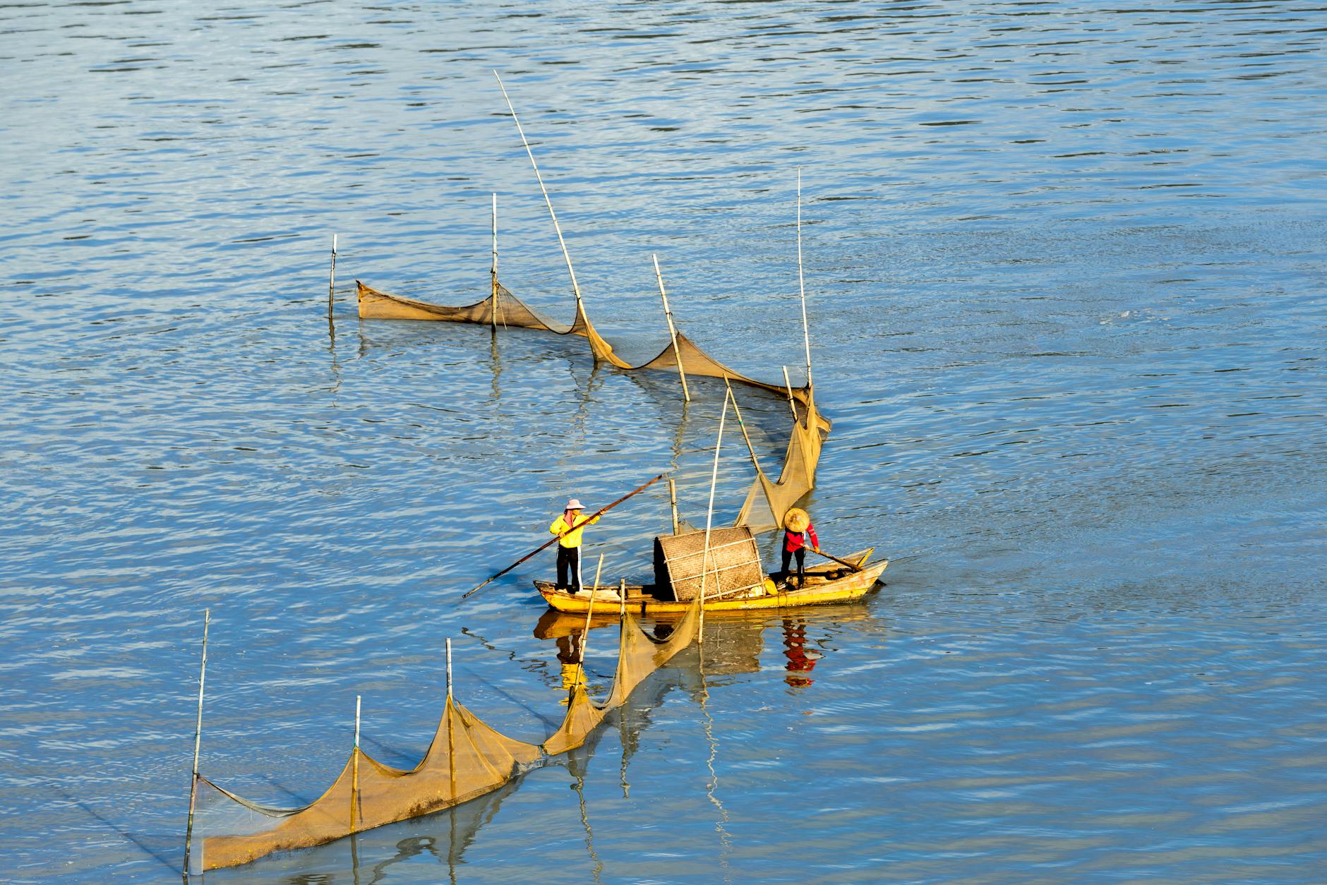 Dwóch tradycyjnych rybaków łowi siecią na spokojnej rzece