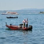 Rybia termika: jak warstwa przejściowa wpływa na brania latem Dwóch wędkarzy łowiących z łodzi na jeziorze Garda w otoczeniu gór