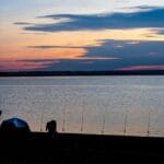 Namiot i wędki nad spokojnym jeziorem o zachodzie słońca