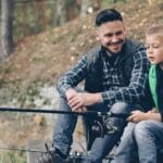 Jak nauczyć dziecko wiązać węzły wędkarskie w 15 minut? Ojciec i syn wędkują nad spokojną rzeką w lesie