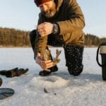 Styczeń: najlepsze miejsca na podlodowe płocie w jeziorach zaporowych i naturalnych Wędkarz łowiący spod lodu na zamarzniętym jeziorze zimą